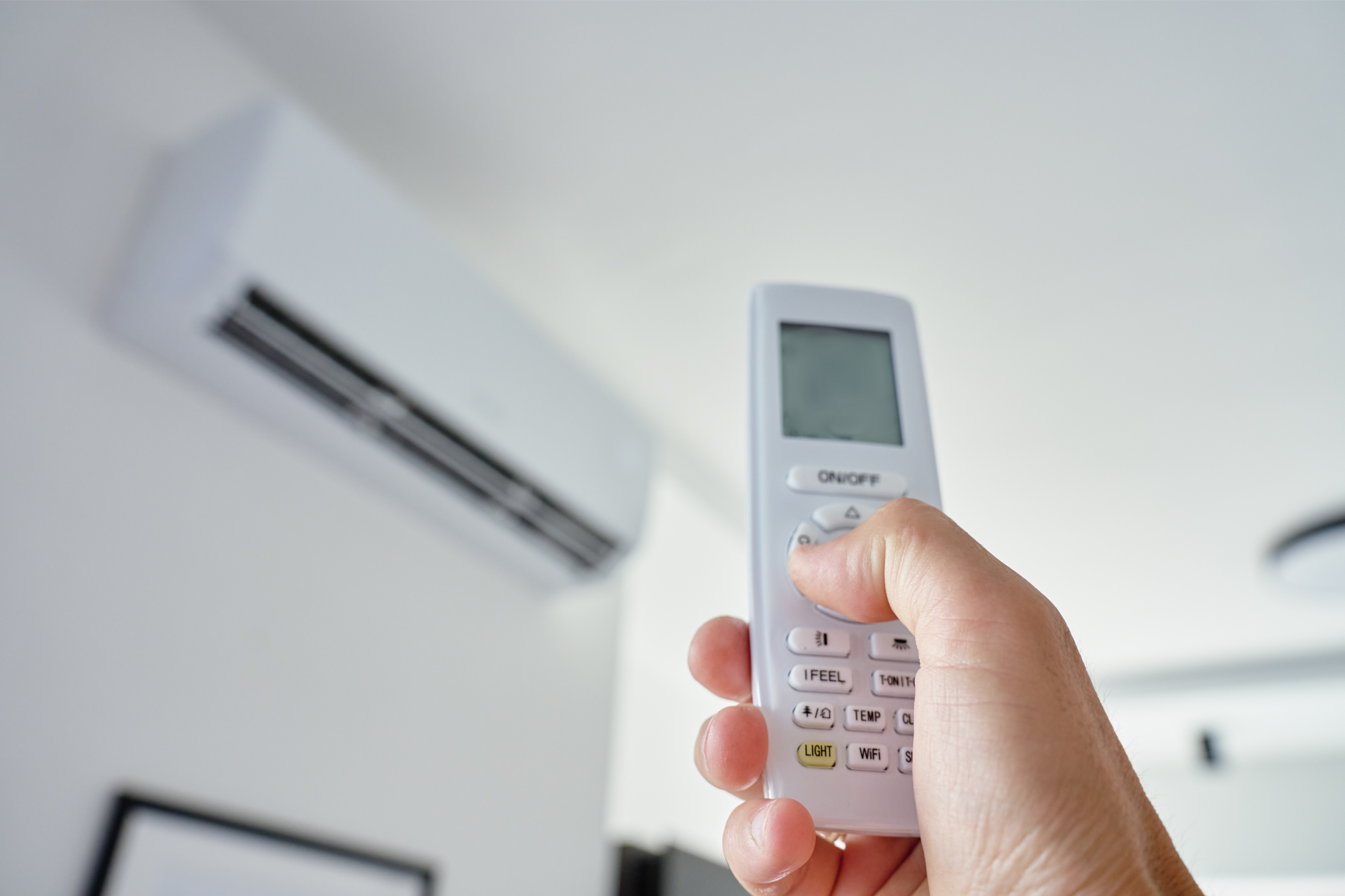 person using a remote on a mini split heat pump